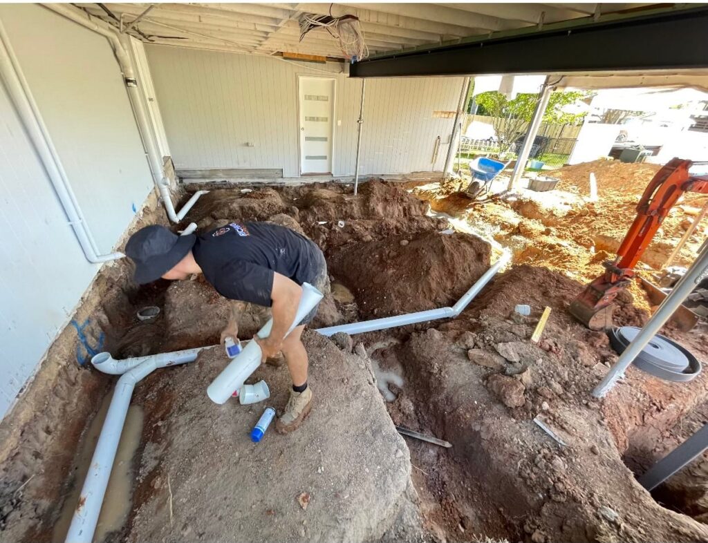 Plumber repairing a blocked drain in Ipswich by installing underground PVC pipes during site excavation